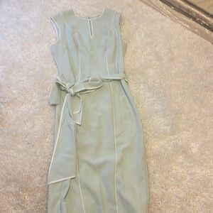 Pale green sleeveless dress with white piping and toe sash.